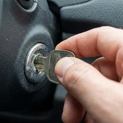 Hand trying to turn a key in a car ignition that won't rotate